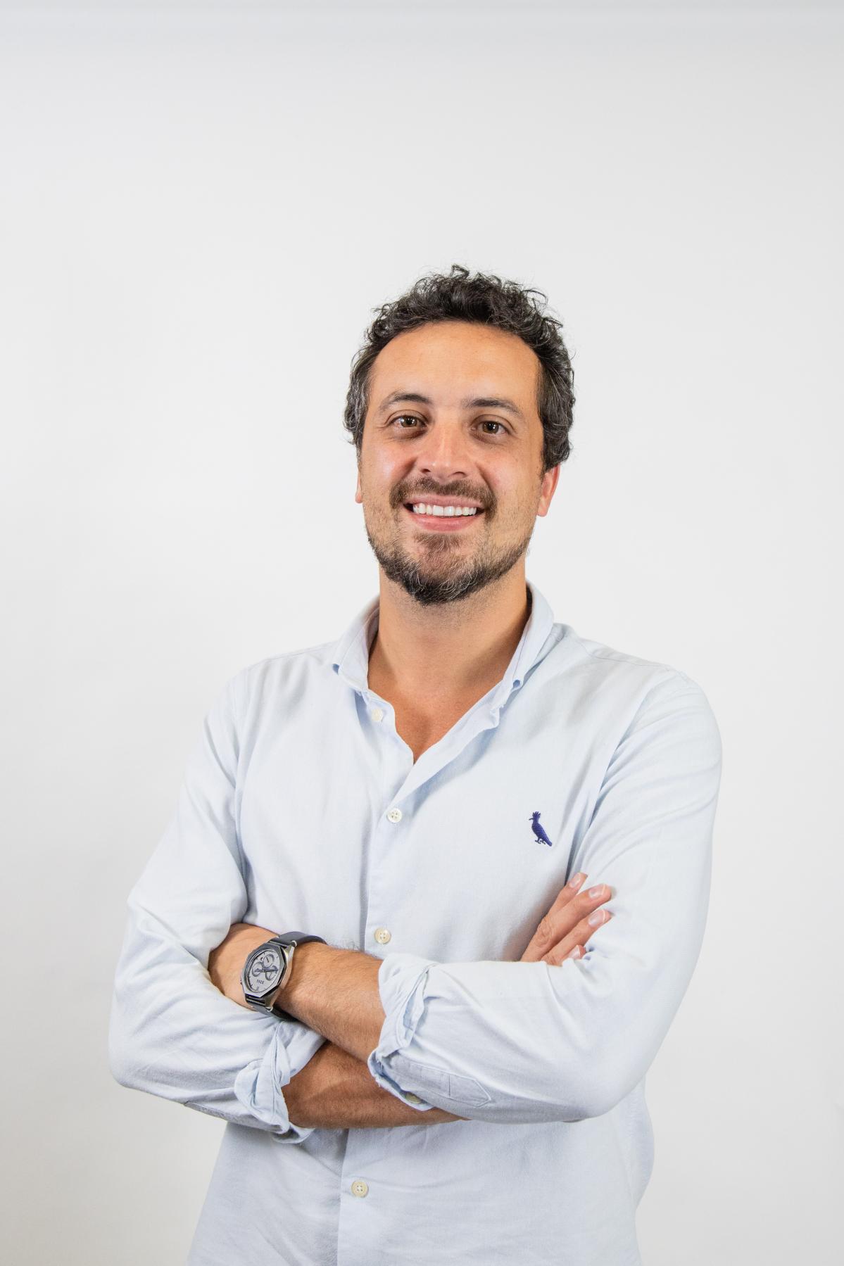 Alexandre Furlan Braz de braços cruzados, em fundo claro
