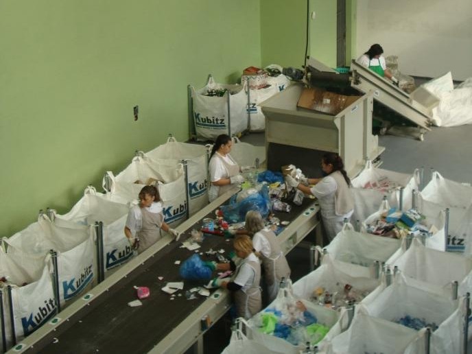 Esteira de triagem de resíduos na central de operação, com equipe separando material